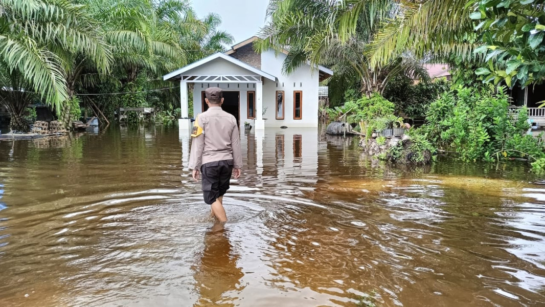Bripka Noprizal,SH Bhabinkamtibmas Desa Sering memantauan debit air sungai Kampar yang mulai menggenangi areal pemukiman warga