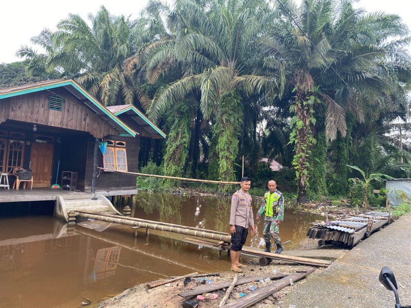 Bhabinkamtibmas Bripka Denny Pritama, SH bersama Babinsa Sertu Pendik Kalpiko memastikan masyarakat yang berada di bantaran sungai Kampar aman