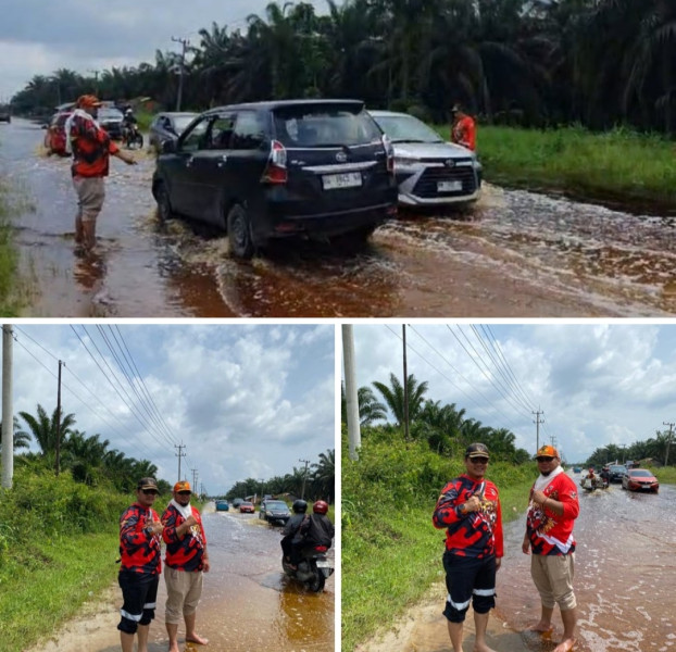 MPC pemuda Pancasila kabupaten Pelalawan bantu kendaraan yang hendak melintas agar tidak keluar jalur akibat kenangan banjir